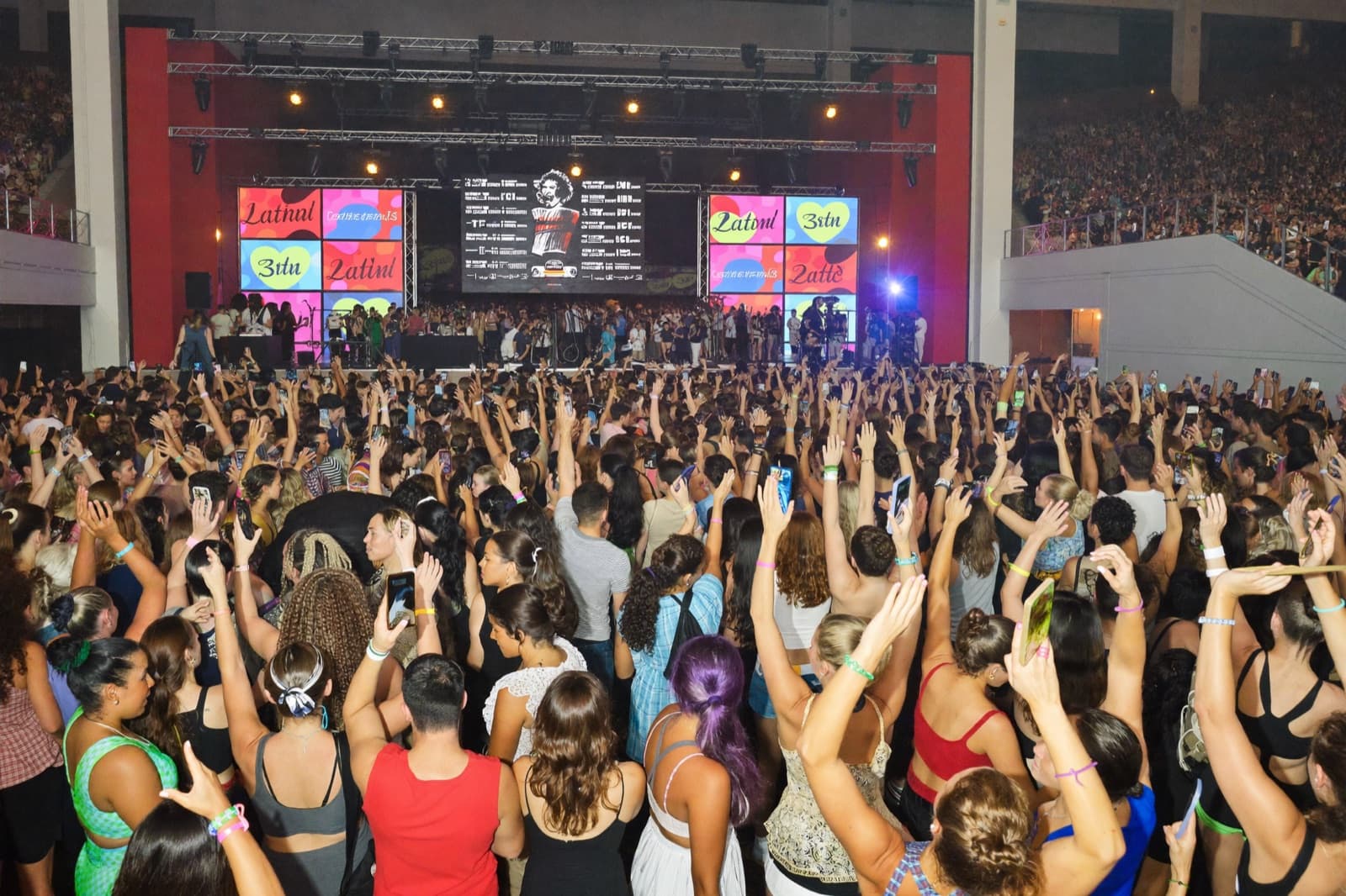 A packed Latin dance festival ballroom under dramatic stage lights
